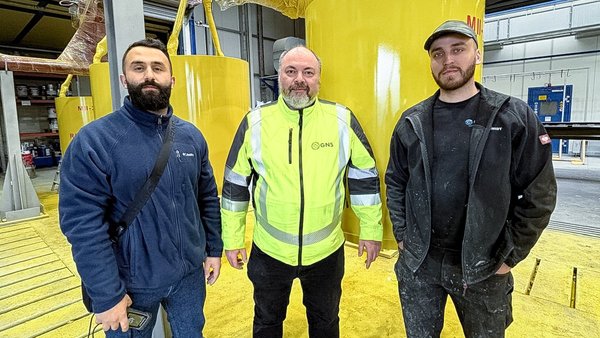 Teammitglieder von GREIS und GNS vor beschichteten gelben Hochdruckkomponenten.