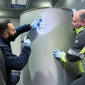 Techniker inspizieren ein beschichtetes Teil der Fertigungshalle.